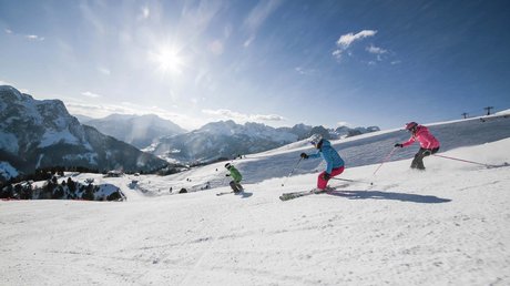 Meteo, Moena, Soraga, Latemar: tutto nella nostra gallery Tre sciatori che scendono una pista innevata con montagne sullo sfondo