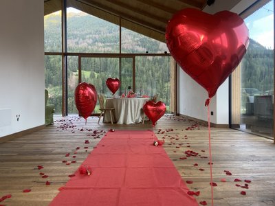 Escursioni da Moena e molto altro: il nostro programma Decorazione romantica con palloncini a forma di cuore rossi e petali di rosa