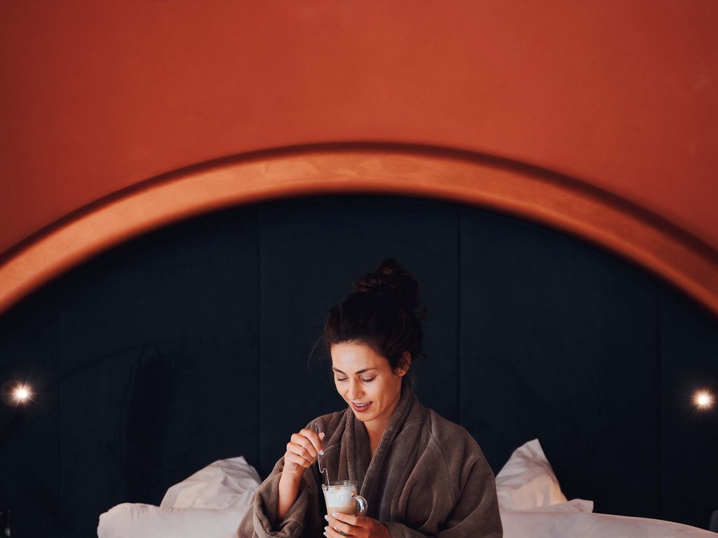Soraga bei Südtirol im Trentino Frau im Bademantel frühstückt mit Gebäck und Kaffee im Bett