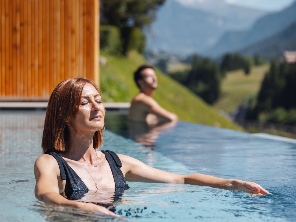 A Soraga il meteo è sempre ottimo per un Day Spa! Donna rilassata in piscina all'aperto con vista sulle montagne