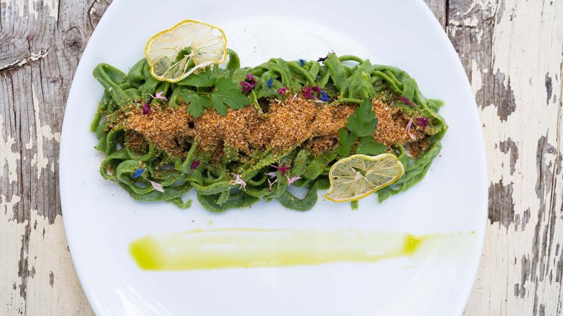 Moena, alberghi da sogno, panorama? C’è l’Hotel Latemar! Pasta verde con pangrattato, fette di limone essiccato e erbe su piatto bianco
