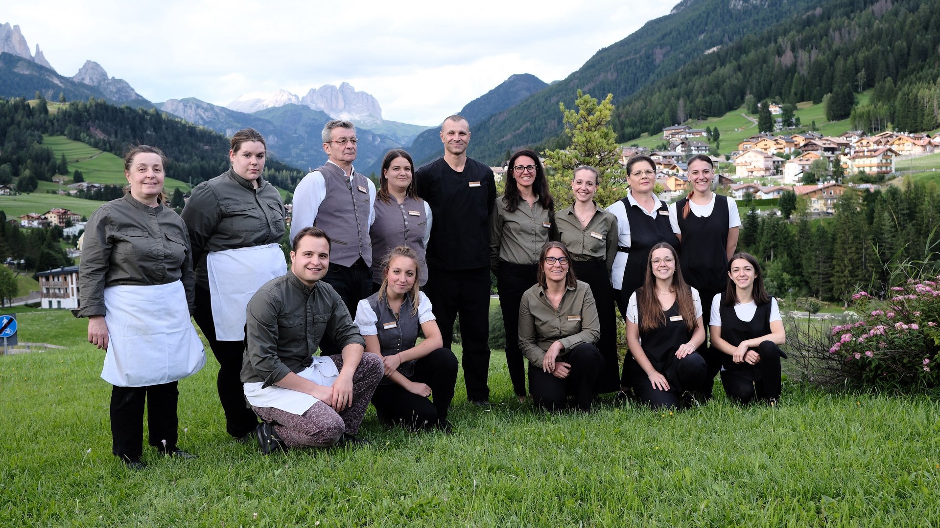 Gruppo di persone in divisa sul prato con vista montagna e villaggio