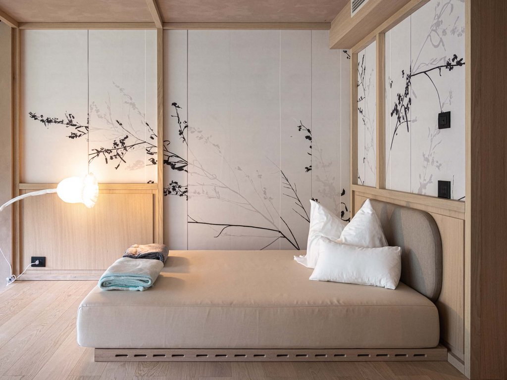 Hotel Latemar con vista sulle Dolomiti Camera da letto con letto beige, cuscini bianchi e pareti decorate con motivi floreali