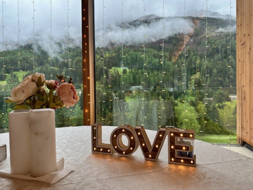 Hotel Latemar mit Dolomitenblick Beleuchteter LOVE Schriftzug auf Tisch mit Berg- und Wolkenblick
