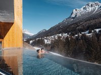 Soraga di Fassa: Wetter Paar im beheizten Pool mit Blick auf verschneite Berge und Dorf