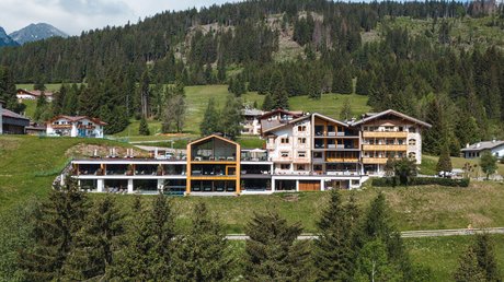 Picture gallery Modern mountain hotel surrounded by trees and green hills under a cloudy sky