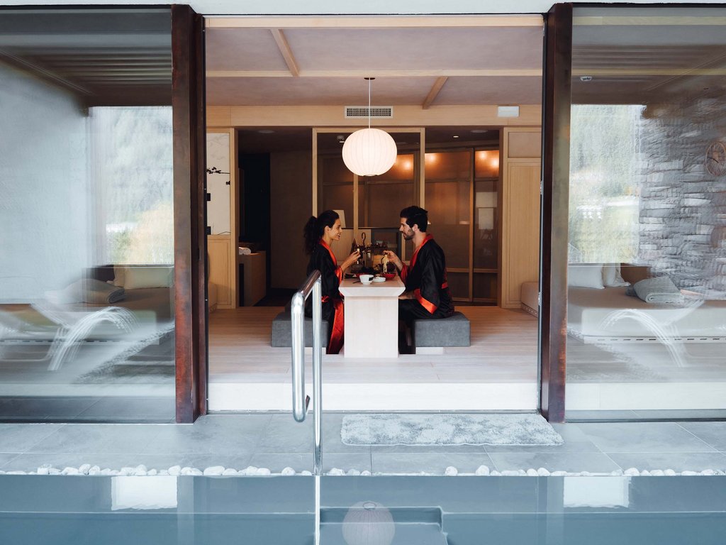 Urlaub im Fassatal: Erholung pur Paar in Kimonos isst in modernem Raum mit Pool davor