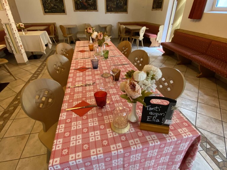 Dalla webcam il Latemar è bello, ma dal vivo è un sogno! Sala da pranzo con tavolo lungo apparecchiato e decorazioni floreali