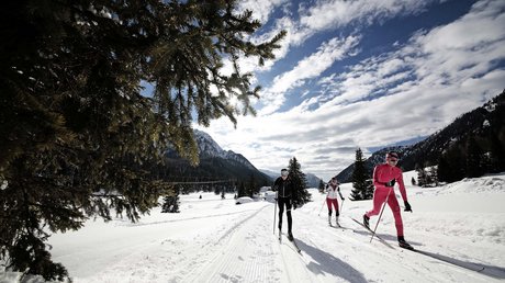 Meteo, Moena, Soraga, Latemar: tutto nella nostra gallery Tre sciatori di fondo in abbigliamento sportivo su pista innevata con montagne sullo sfondo