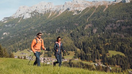 Picture gallery Couple hiking on a grassy field with mountains in the background