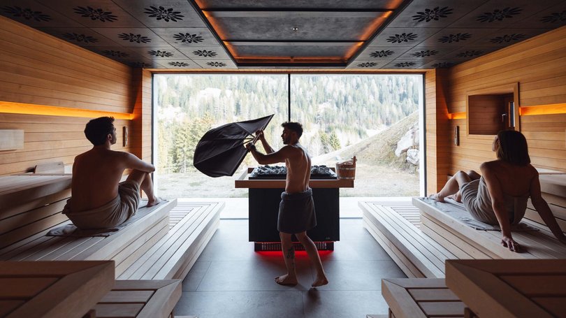 Val di Fassa: wandern, biken, erleben Innenraum einer modernen Sauna mit drei Personen in Handtüchern