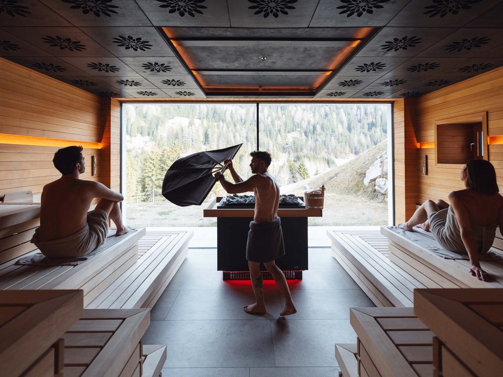 Al Latemar, dopo le passeggiate: relax nella Spa Oniro Interno di sauna moderna con tre persone avvolte in asciugamani