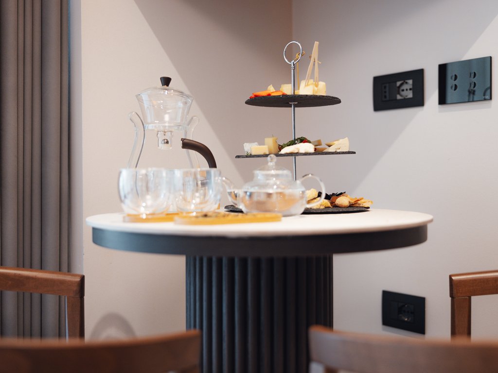 Sulla pista ciclabile, da Moena alla vostra oasi romantica Tavolo con set da tè in vetro e vassoio a più piani con stuzzichini